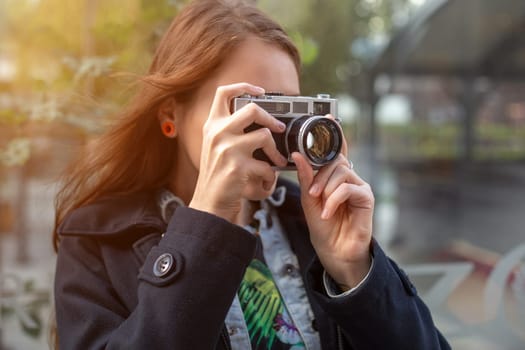 Portrait of a pretty young tourist taking photographs with vintage retro camera. Street style. Life style