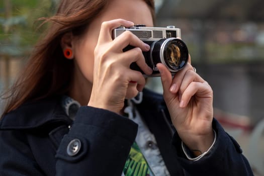 Portrait of a pretty young tourist taking photographs with vintage retro camera. Street style. Life style