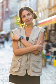 Portrait of happy pretty young woman smiling friendly, glad expression looking at camera dreaming, resting, relaxation feel satisfied good news outdoors. Girl in urban city sunshine street. Vertical