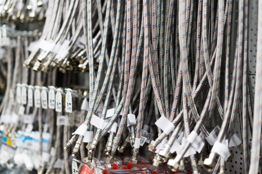 Closed up braided stainless steel texture of flexible hose arranged in row against white wall.