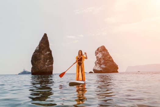 Close up shot of beautiful young caucasian woman with black hair and freckles looking at camera and smiling. Cute woman portrait in a pink bikini posing on a volcanic rock high above the sea