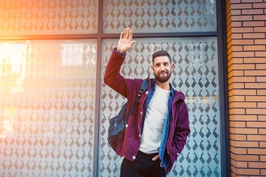 Street fashion model tourist man outdoor. Waiting friends on grunge wall. Man wearing black bag and purple jacket, autumn.