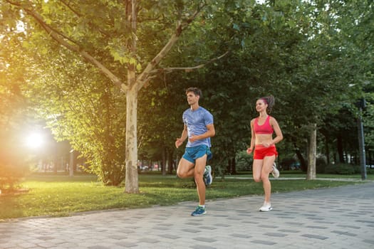 Portrait of cheerful caucasian couple running outdoors. Sun flare.