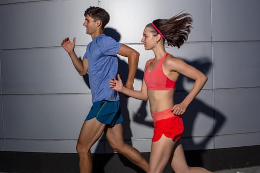 Active young couple jogging side by side in an urban street during their daily workout in a health and fitness concept. Healthy lifestyle