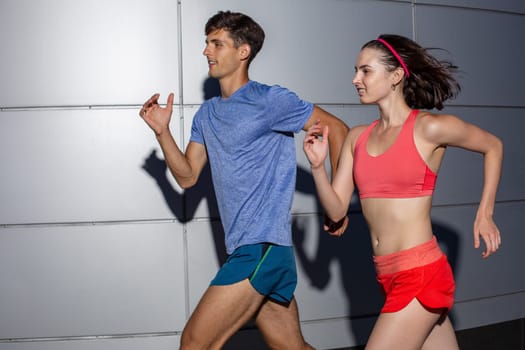 Active young couple jogging side by side in an urban street during their daily workout in a health and fitness concept. Healthy lifestyle