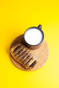 Breakfast bread and cup of milk on yellow and blue background