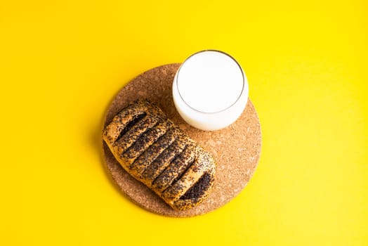 Breakfast bread and cup of milk on yellow and blue background