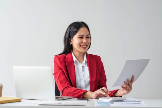 Cheerful business lady working on laptop in office, Asian happy beautiful businesswoman in formal suit work in workplace. Attractive female employee office worker smile...