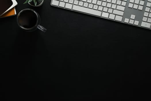 Top view of keyboard, cup of coffee and book on black leather. Copy space for your text.