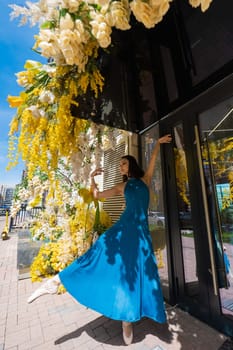 Beautiful Asian ballerina posing against the backdrop of a building decorated with flowers