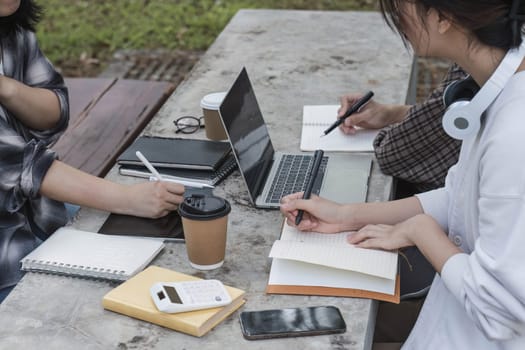 Group of Student working on laptop and record in book together at university. Happy friend successfully completes the thesis report and passed the final exam in asian college...