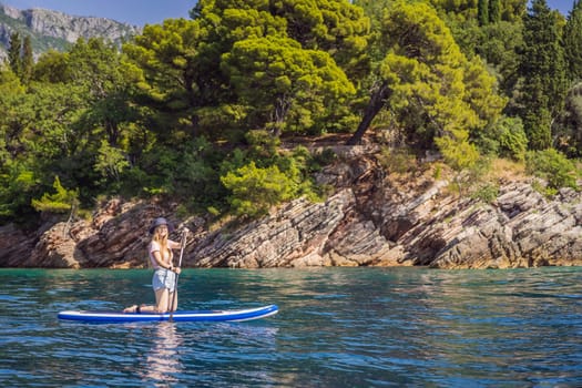 Young women Having Fun Stand Up Paddling in blue water sea near st stefan island in Montenegro. SUP.