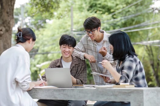 Group of Asian college student reading books and tutoring special class for exam on grass field at outdoors. Happiness and Education learning concept. Back to school concept. Teen and people theme...