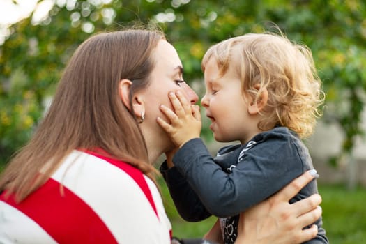 Happy mother and son hugging in love playing in the park.