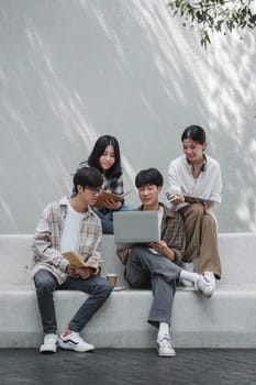 Group of Asian college student reading books and tutoring special class for exam on grass field at outdoors. Happiness and Education learning concept. Back to school concept. Teen and people theme...