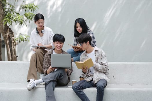 Group of Asian college student reading books and tutoring special class for exam on grass field at outdoors. Happiness and Education learning concept. Back to school concept. Teen and people theme...