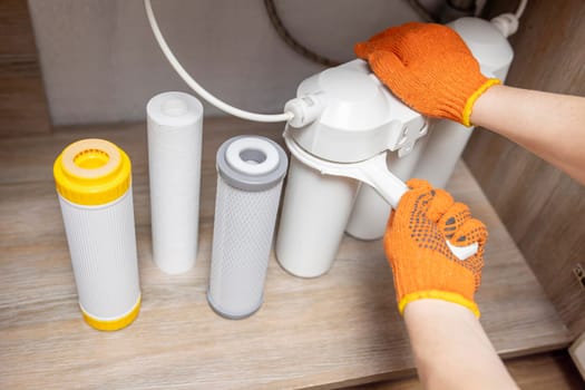 Plumber installs or change water filter. Replacement aqua filter. Repairman installing water filter cartridges in a kitchen. Clean water at home.