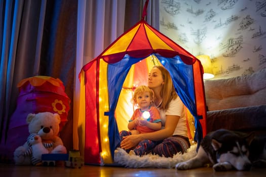 Happy loving family. Young mother and her son boy play in children room at the bedtime. Mom and lovely child are having fun with flashlights indoors. Family concept.