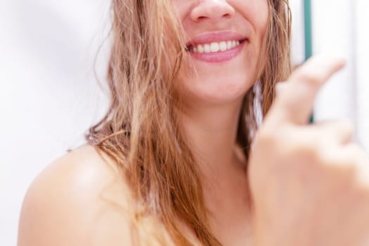 Close up half face cropped portrait of smiling woman's with wet hair after shower in shower cabin at home.