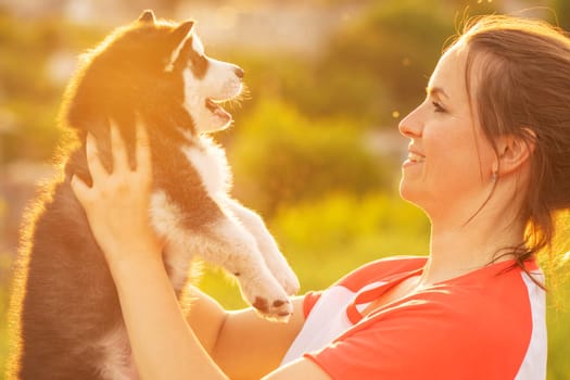 Beautiful young caucasian woman is playing with her puppy dog outdoor. Animal, friendship, people and love concept.