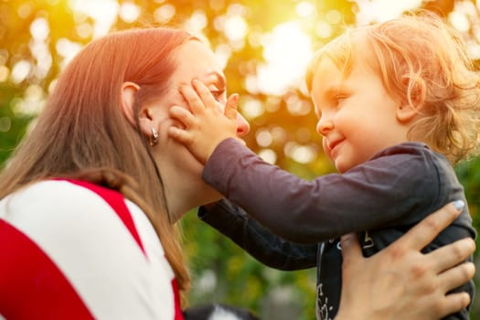 Happy mother and son hugging in love playing in the park.