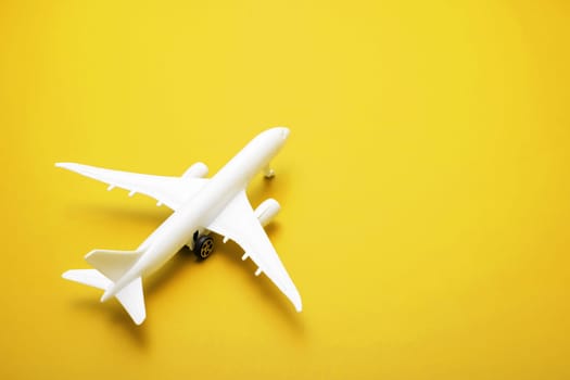 White model of passenger plane on yellow background , travel concept. Traveling by plane.