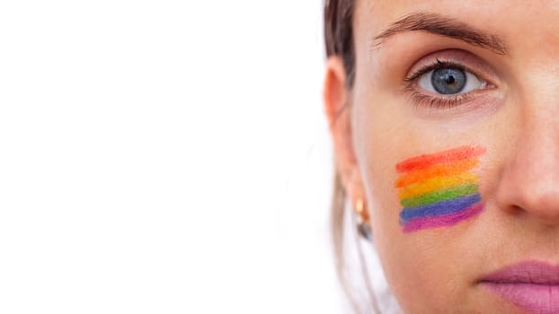 Portrait of a young smiling woman with LGBT flag painted on her cheek. Theme of equality and freedom of choice.