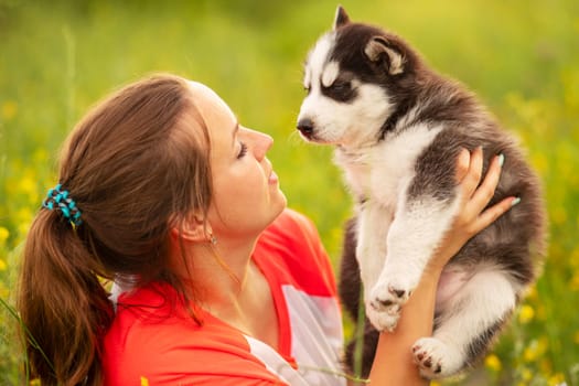 Beautiful young caucasian woman is playing with her puppy dog outdoor. Animal, friendship, people and love concept.