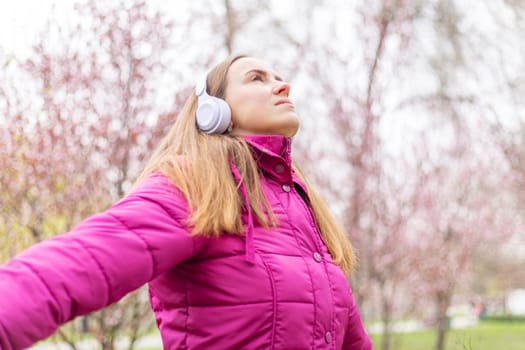 Relaxed woman wearing headphones breathing fresh air listening to music in a forest or park