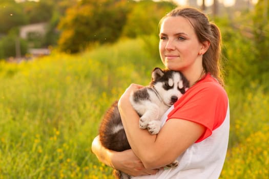 Beautiful young caucasian woman is playing with her puppy dog outdoor. Animal, friendship, people and love concept.