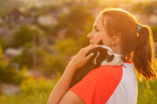 Beautiful young caucasian woman is playing with her puppy dog outdoor. Animal, friendship, people and love concept.