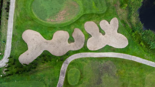 Aerial view of golf course with a rich green turf beautiful scenery. Sand bunkers at a beautiful golf course by the pond.