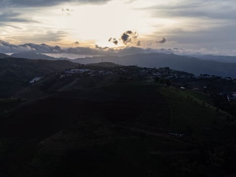 Aerial view of beautiful sunrise or sunset sky and rural villages. Village landscape in misty valley and mountain clouds in thailand.