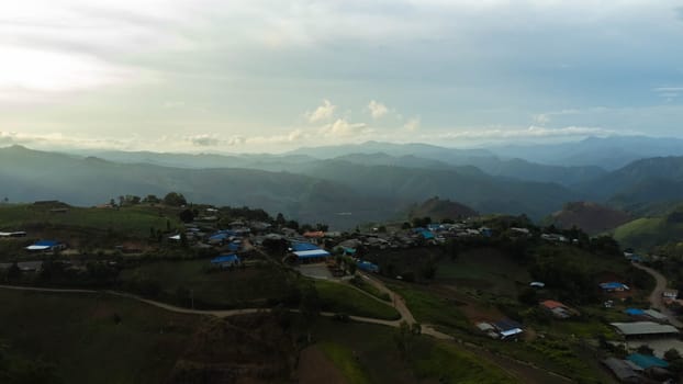 Aerial view of beautiful sunrise or sunset sky and rural villages. Village landscape in misty valley and mountain clouds in thailand.