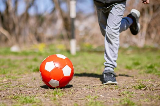 Boy is playing with soccer ball on a footballs field in the park. Kids activities.