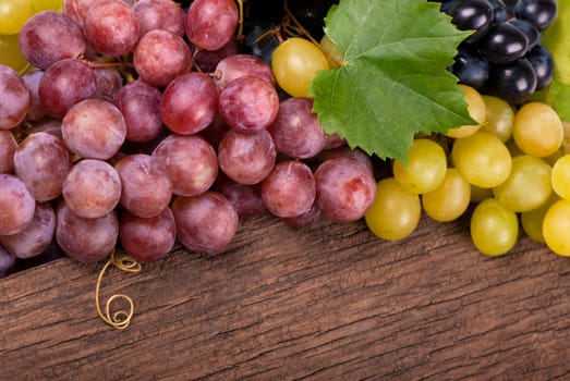 Bunches of fresh ripe red grapes on a wooden textural surface.