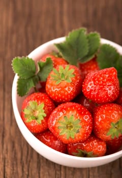 bowl with fresh strawberries on rustic table on wooden