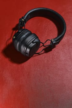 Wireless black headphones on a red background. View from above.