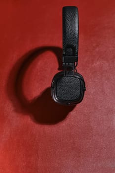 Wireless black headphones on a red background. View from above.