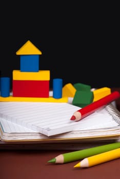 board, books, pencils, opened empty notebook against a dark background