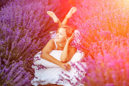 Woman lavender field. A middle-aged woman lies in a lavender field and enjoys aromatherapy. Aromatherapy concept, lavender oil, photo session in lavender.