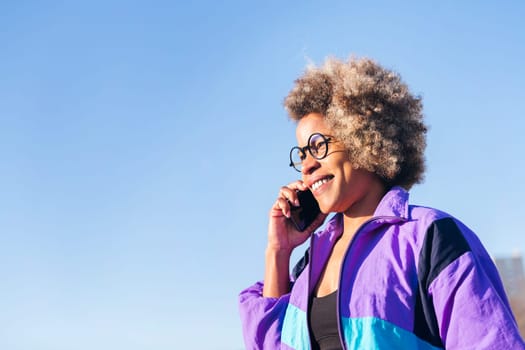 african american woman in sportswear talking by phone, concept of technology of communication and urban sport, copy space for text