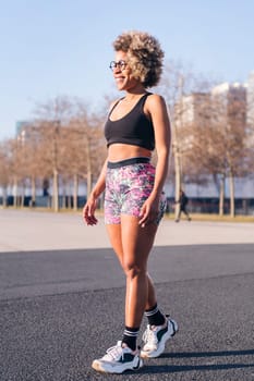 vertical portrait of an african american woman in sportive summer clothes ready to run outdoors, concept of active lifestyle and urban sport