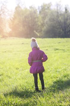 Little girl walks outdoors in sunny day. Early spring in countryside.