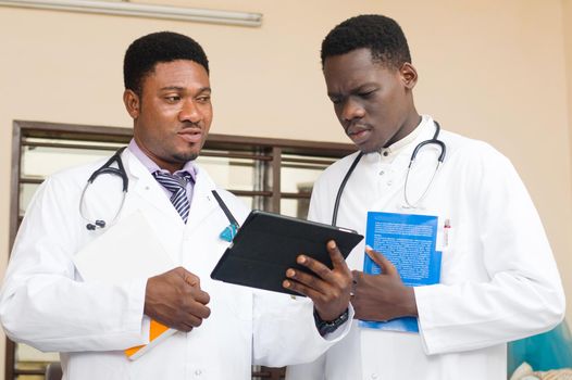 doctor and professor standing talking on a digital tablet at the hospital.