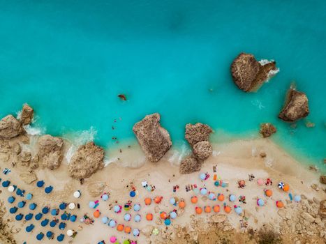 Aerial view of the amazing  idyllic  beach with colorful umbrellas, sunbed and people who sunbathing and swiming.