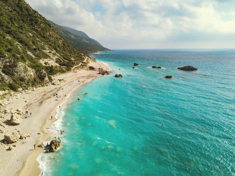 Aerial view of the wild sandy beach with rocks in the sea on a sunny day. 