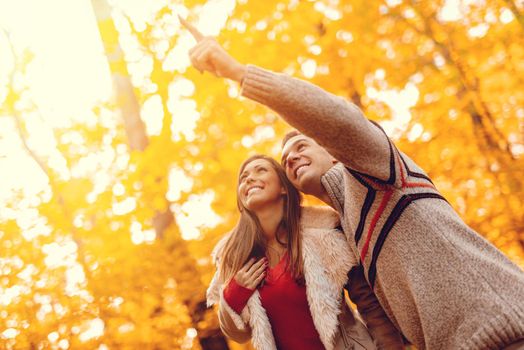 Beautiful smiling couple enjoying in sunny forest in autumn colors.