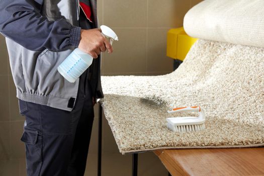 Man Spraying Detergent On Grey Carpet To Remove Stain in professional cleaning service High quality photo