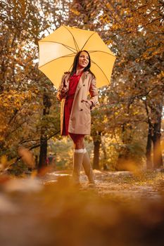 Happy woman with yellow umbrella walking in at beautifu sunny autumn park. 